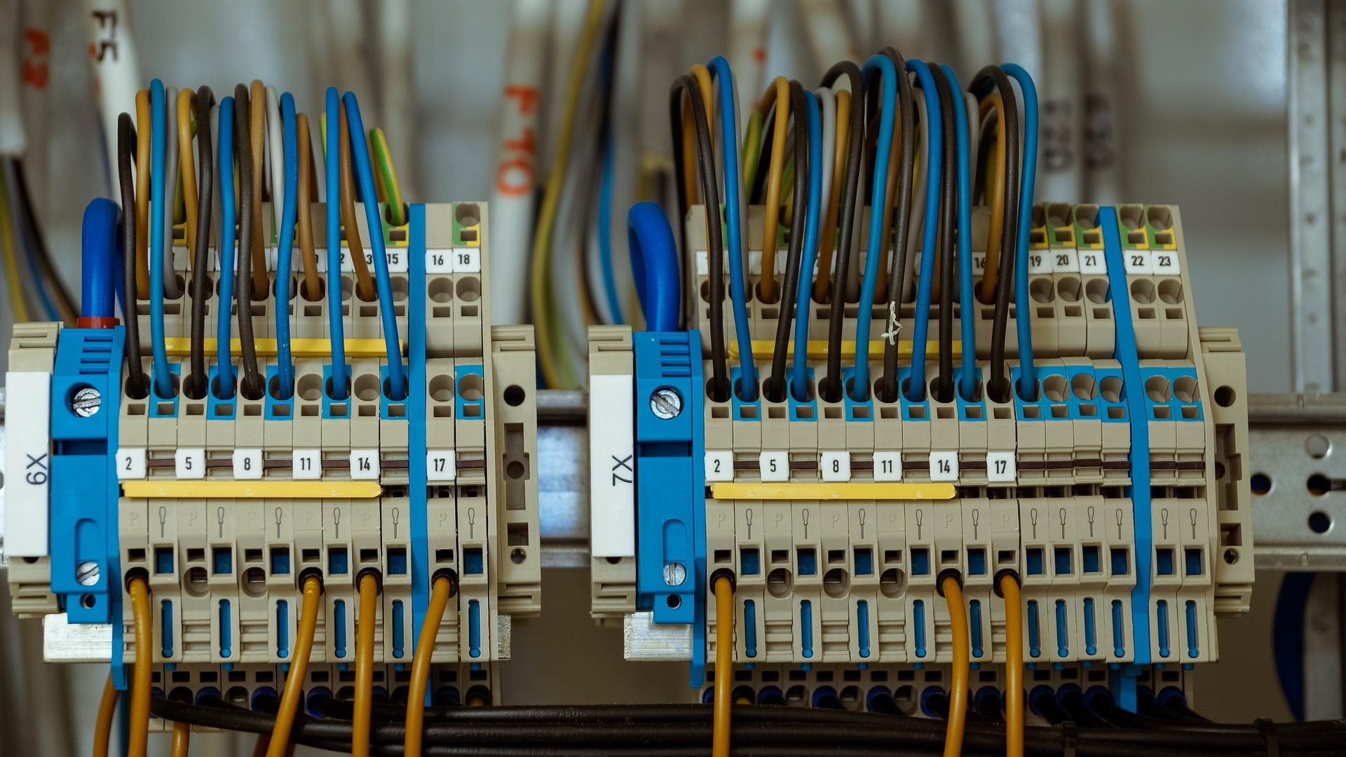 Elektroverteiler mit farbigen Kabeln und Klemmen in einem Schaltschrank für Stromversorgung.